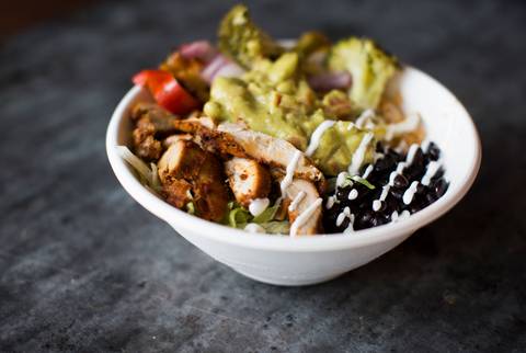 A Mexican bowl with chicken, black beans, guacamole, and pickled onions over rice